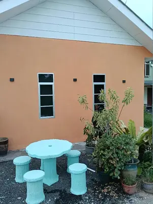 a table and four stools in front of a building at D'Permata Roomstay Kampung Pelet in Kubang Semang