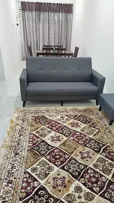 a blue couch in a living room with a rug at Homestay Kak Rose 2 Kuala Lipis in Kampong Temperah