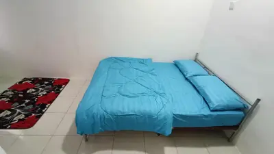 a blue bed in a room with a rug at Homestay Kak Rose 2 Kuala Lipis in Kampong Temperah