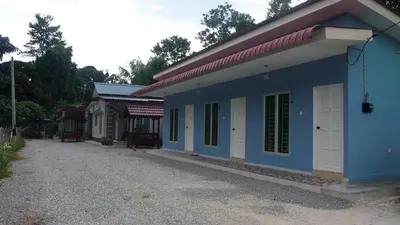a blue building with green windows on a gravel road at D'Binjai Homestay & Roomstays Kuala Kangsar in Kuala Kangsar