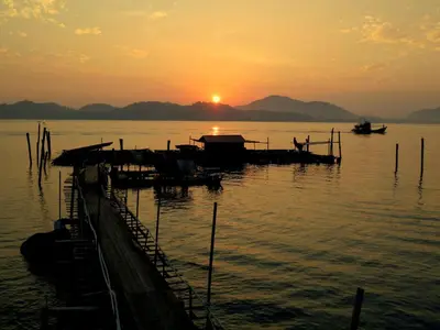 a sunset over a body of water with boats at Pangkor Fish House in Pangkor