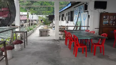 a table and red chairs sitting outside of a restaurant at Pangkor Fish House in Pangkor