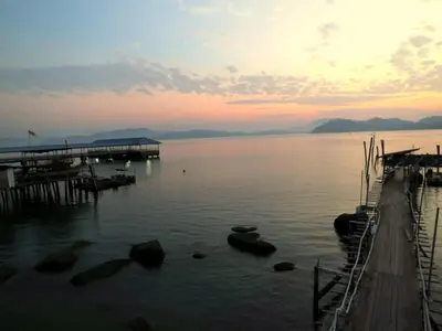a sunset over a lake with a dock at Pangkor Fish House in Pangkor