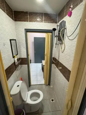 a small bathroom with a toilet and a shower at Wika Homestay in Kulim