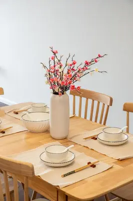 a wooden table with plates and flowers in a vase at Serene Japandi Family Retreat 2-7pax &Sunrise View in Brinchang
