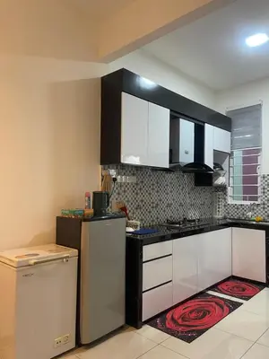 a kitchen with white cabinets and a refrigerator at Homestay Sakura in Padang Serai