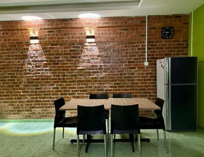a wooden table and chairs in front of a brick wall at Bola-Bola DHomestay in Kepala Batas