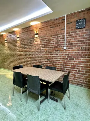 a wooden table with chairs and a clock on a brick wall at Bola-Bola DHomestay in Kepala Batas