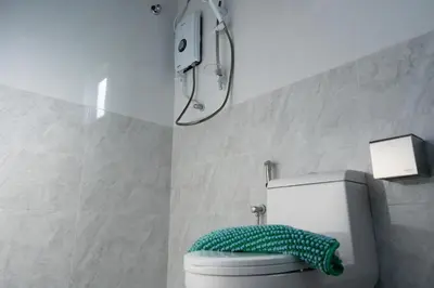 a bathroom with a toilet with a green towel on it at Bricks Guesthouse in Tanah Rata
