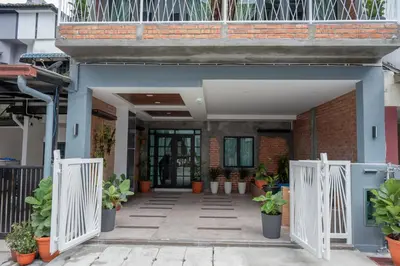 a building with a white gate and potted plants at Bricks Guesthouse in Tanah Rata