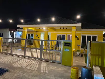 a yellow home with a gas pump in front of it at Yellow Retreat House Homestay Batu Gajah in Batu Gajah