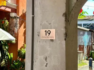 a sign on the side of a wall with a house at Li's Inn in George Town