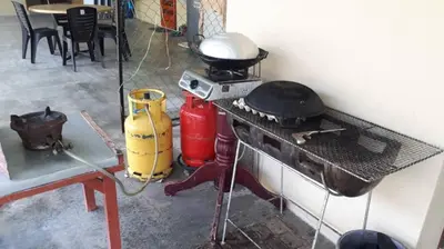 a kitchen with an old stove and a table with aperature at Pangkor Homestay in Pangkor