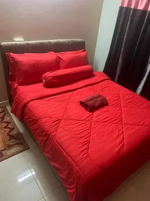 a red bed with red sheets and pillows on it at Airis Homestay Bertam Perdana in Kepala Batas