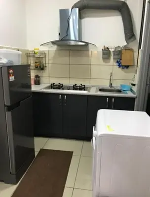 a kitchen with black cabinets and a sink and a refrigerator at Opah Palas Homestay in Brinchang