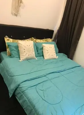 a bed with blue sheets and pillows in a room at Opah Palas Homestay in Brinchang