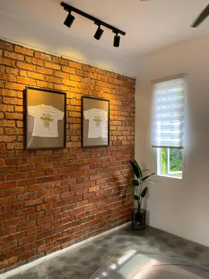 a brick wall with two pictures and a window at RumaTisa in Teluk Intan
