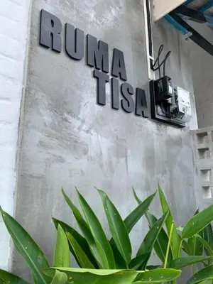 a sign on a wall with a plant at RumaTisa in Teluk Intan