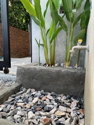 a rock garden with a faucet and some plants at RumaTisa in Teluk Intan