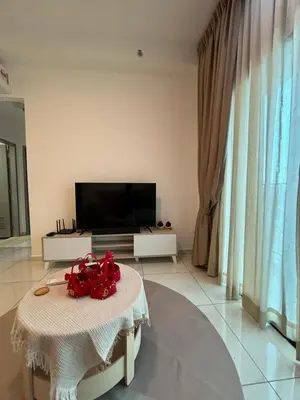 a living room with a table and a tv at Cozy House in Batu Kawan