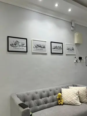 a couch in a living room with four pictures on the wall at yasmins homestay in Sitiawan