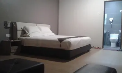 a bedroom with a bed with white sheets and a toilet at Welcome Inn GM in Gua Musang