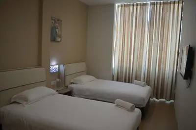two beds in a small room with a window at Welcome Inn GM in Gua Musang