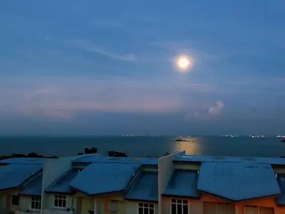 a full moon rising over houses and the ocean at Shamrock Boutique Villa - Stay for 12 person in Batu Ferringhi