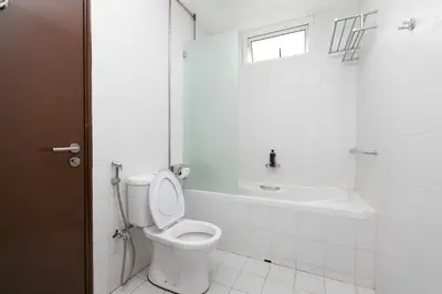 a white bathroom with a toilet and a bath tub at GeorgeTown Codrington 6BR KTV BBQ Pool Bungalow 28Pax in George Town
