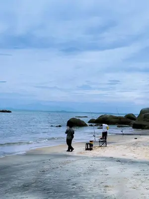 two people standing on the beach with fishing equipment at 25 guests batu feringhi Miami beach Miami Villa in Batu Ferringhi