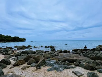 a person sitting on the rocks on the beach at 25 guests batu feringhi Miami beach Miami Villa in Batu Ferringhi