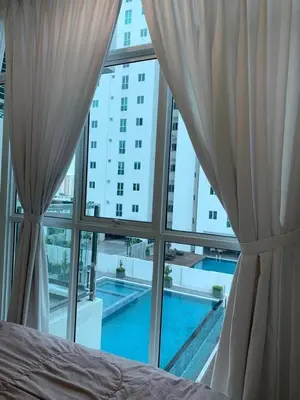 a bedroom with a view of a swimming pool seen through windows at Straits Garden Suites in Jelutong