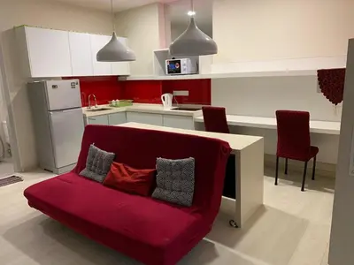 a kitchen with a red couch with pillows on it at Straits Garden Suites in Jelutong
