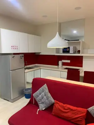 a living room with a red couch in a kitchen at Straits Garden Suites in Jelutong