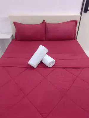 a pink bed with two white towels on it at Skyn 2 smartstay in Ipoh