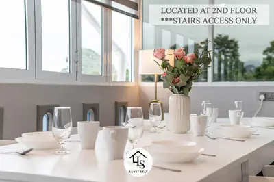 a white table with a vase of flowers and glasses at IPOH CAIP TownHouse UpperUnit 4R3B Ipoh Tambun 10Pax by Luvit Stay in Ipoh