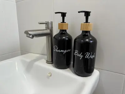 two black bottles sitting on top of a sink at Bright Apartment in Klebang in Ipoh