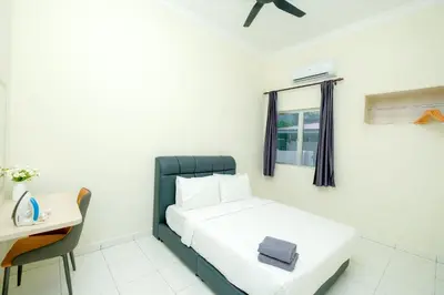 a small bedroom with a bed and a desk at Arista Guest House in Pangkor