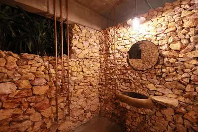 a stone bathroom with a mirror and a stone wall at The Wildwood Retreat KKB in Kuala Kubu Baharu