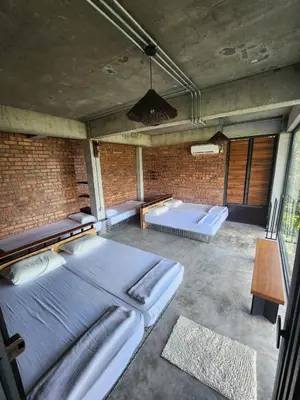 two beds in a room with a brick wall at The Wildwood Retreat KKB in Kuala Kubu Baharu