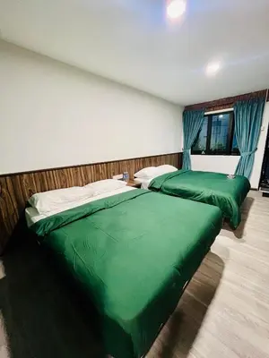 two beds in a bedroom with green sheets at Big Dreams Hotel in Tanah Rata