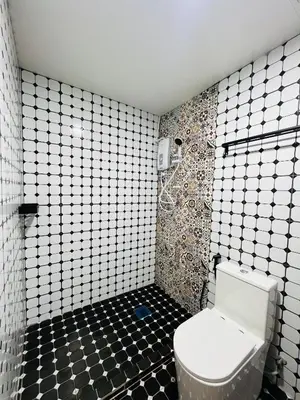 a bathroom with a toilet and black and white tiles at Big Dreams Hotel in Tanah Rata