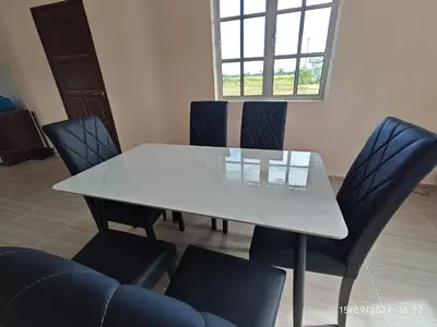 a dining room table and chairs with a white table at Syakeel Homestay Bandar Bharu, Parit Buntar & Nibong Tebal in Bandar Baharu