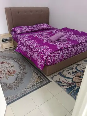 a bedroom with a purple bed and two rugs at Auni Homestay in Raub