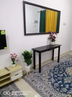 a mirror on a wall with a table and a rug at Auni Homestay in Raub