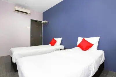 two beds with red pillows in a room at De Hotel in Teluk Intan