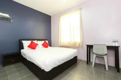 a bedroom with a bed with red pillows and a desk at De Hotel in Teluk Intan