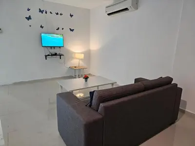 a living room with a couch and a tv at Marina Island Apartment, Lumut in Lumut