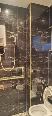a bathroom with a black tiled wall with a toilet at Adik Aisyah goldblack homestay cameron highlands in Tanah Rata