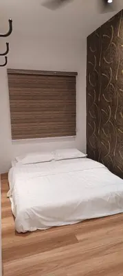 a bedroom with a white bed with a wooden floor at Adik Aisyah goldblack homestay cameron highlands in Tanah Rata